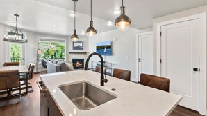 Una cocina moderna con una isla central, iluminación colgante y vistas al exterior.