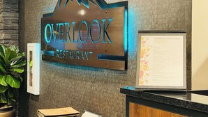 Placa de restaurante com desenho de montanha e o nome 'OVERLOOK RESTAURANT' iluminado em azul.