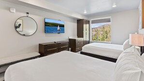 Habitación de hotel moderna con dos camas, un televisor, un espejo, un aparador y una ventana con vistas al exterior.