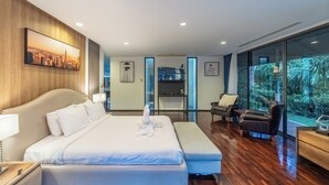 A modern hotel room with a large bed, a seating area with a view, and a cityscape painting on the wall. - Luxury4BRVillaPrivatePoolGolf Views v145 (Kathu)