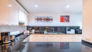 A modern kitchen with a black countertop, white cabinets, and a large window. - Luxury4BRVillaPrivatePoolGolf Views v145 (Kathu)