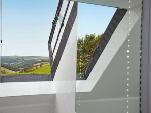 A skylight window with a view of rolling hills and trees. - 3 bedroom accommodation in Brixham (Brixham)