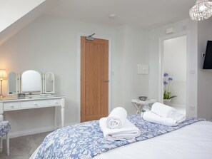 A bedroom with a bed, a wooden door, a white dresser, and a small table with a bowl.