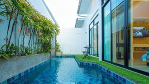 A modern indoor swimming pool with clear blue water, surrounded by a tiled edge and a small grassy area. - Private pool great location v144 (Rawai)