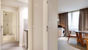 A hotel room with a bathroom, a kitchenette, and a dining area with a table and chairs. - Appartement cosy - Porte de Versailles (Paris)