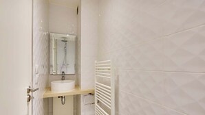 A bathroom with a white sink, mirror, and towel rack. - Appartement cosy - Porte de Versailles (Paris)