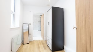 Ein Flur mit großem Kleiderschrank, Spiegel und Heizkörper.