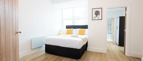 A bedroom with a bed, a window, a radiator, and a door.
