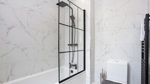 Ein Badezimmer mit einer gläsernen Duschkabine, einer weißen Toilette und einem Handtuchhalter.