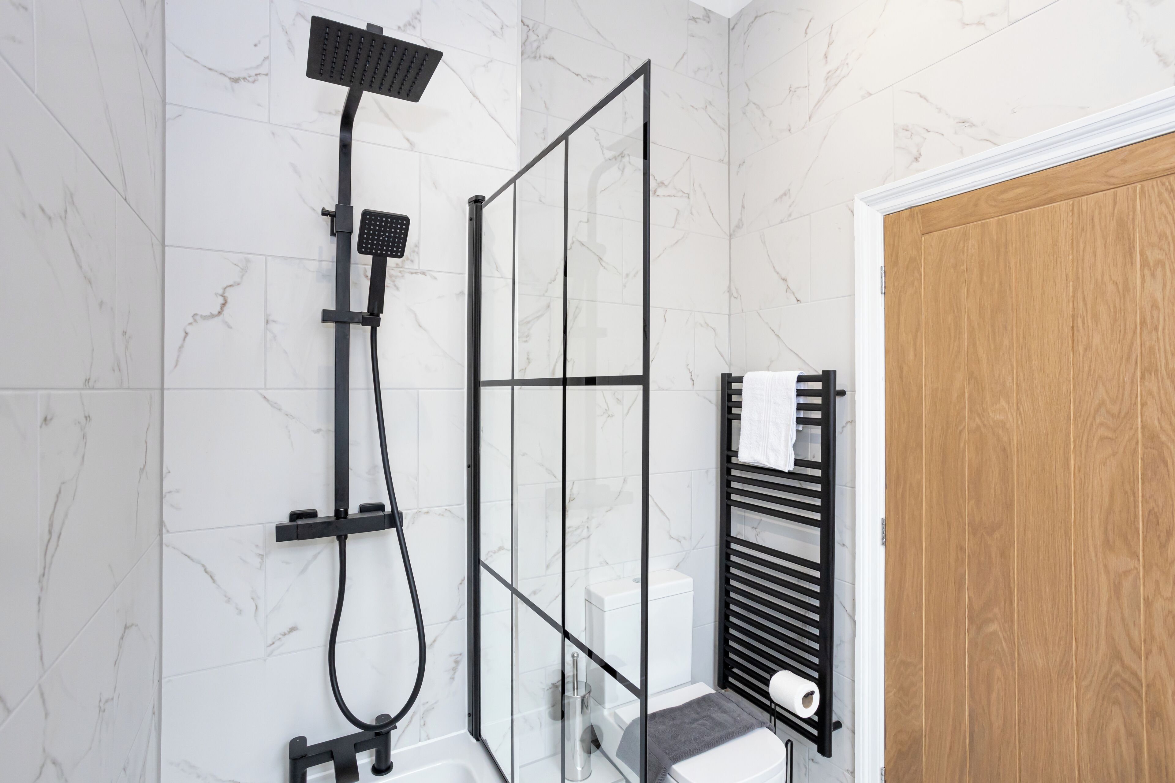 Un baño moderno con cabina de ducha de vidrio, inodoro y barra para toallas.
