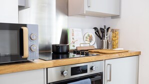 Eine moderne Küche mit Mikrowelle, Herd, Backofen und einer Holzarbeitsplatte.