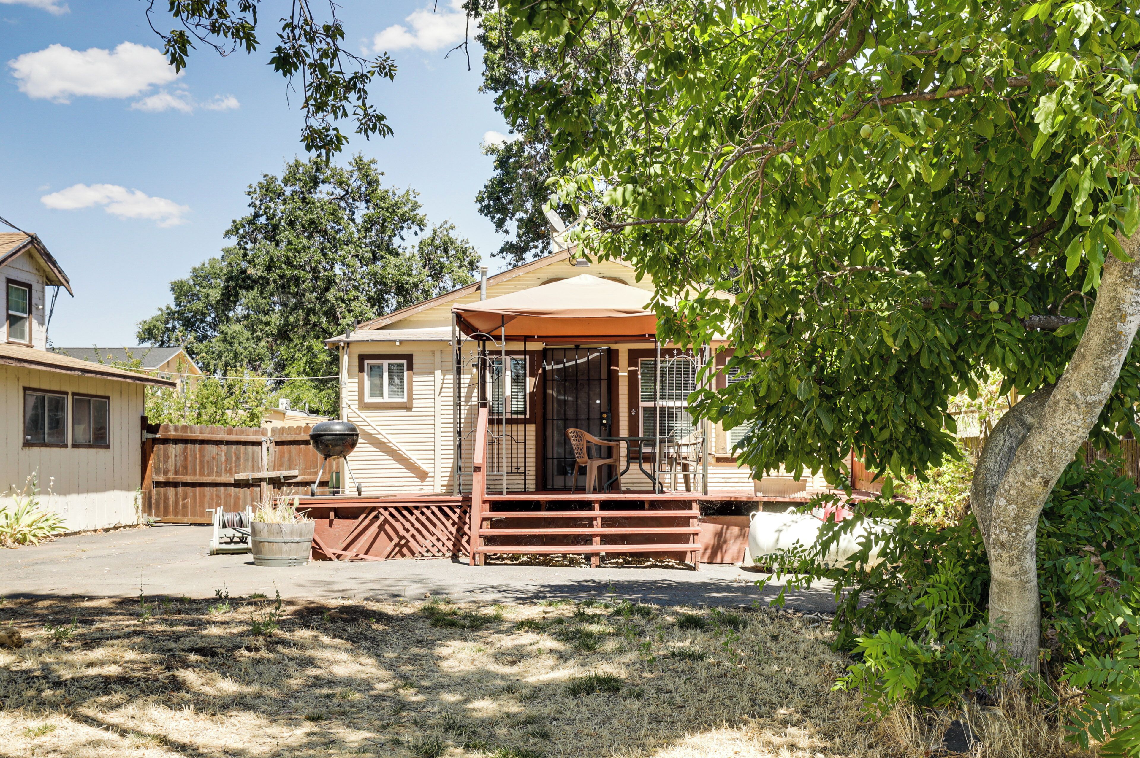 Ein zweigeschossiges Haus mit einer Veranda, einem Holzzaun und einem Baum im Vordergrund.