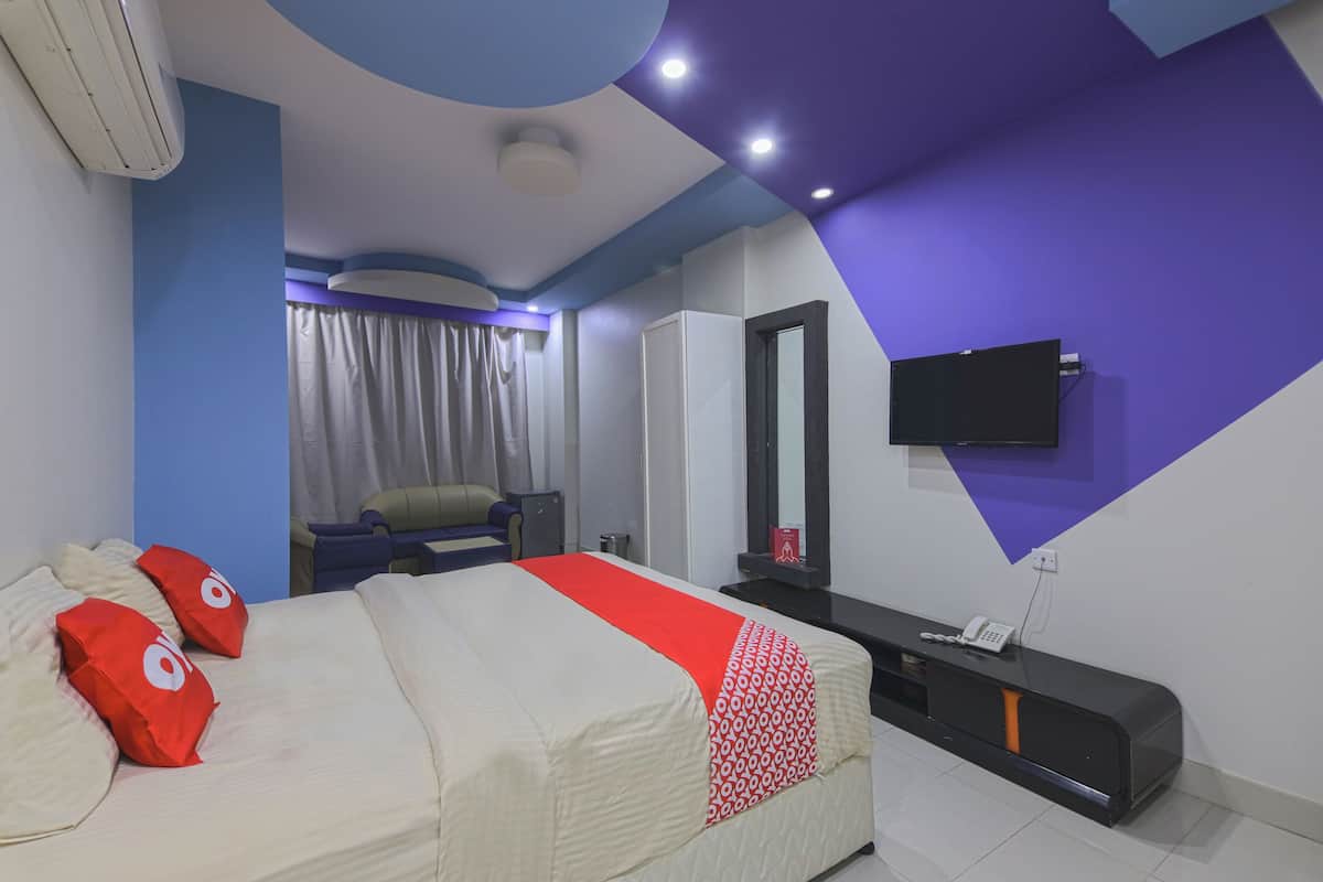 Une chambre d’hôtel avec un lit, un bureau, une télévision et une fenêtre avec des rideaux.