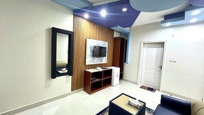 A modern living room with a TV mounted on a marble wall, a wooden entertainment unit, a sofa, and a coffee table. - Al Bayrahaa Checkmyguest Muscat  (Seeb)