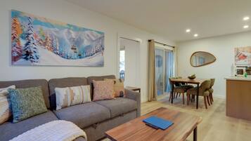 A living room with a sofa, coffee table, and a painting of a snowy landscape.
