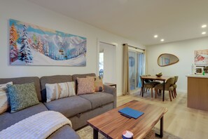 A living room with a sofa, coffee table, and a painting of a snowy landscape. - Walk to Mammoth Village: Chic Mountain Suite 101 (Mammoth Lakes)