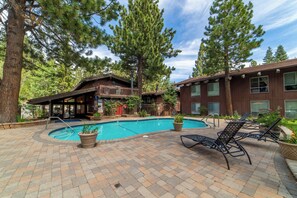 A pool area with lounge chairs and a wooden building with a balcony.
