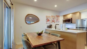 A modern kitchen with a wooden dining table, chairs, and a built-in microwave.