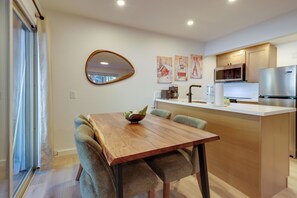 A modern kitchen with a wooden dining table, chairs, and a built-in microwave.