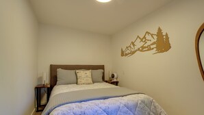 A bedroom with a bed, nightstands, a wall decoration, and a bedside table.