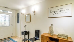 A hallway with a wooden cabinet, a black chair, a mirror, and a framed sign on the wall. - 1/2 Mi to Metrobus Stop! Walkable Petworth Duplex (Washington)