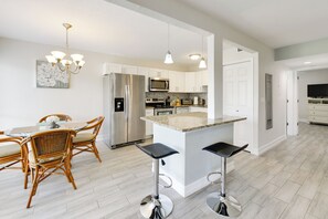 A modern kitchen with white cabinets, stainless steel appliances, and a central island with bar stools. - 3 Mi to Siesta Key Beach: Condo w/ Heated Pool! (Sarasota)
