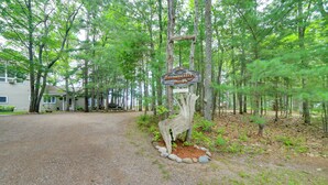 A rustic wooden sign with the text "Welcome to Tranquility Haven" in a forested area with a gravel path leading to a row of houses. - Private Sandy Beach: Lake Superior Group Retreat (Marquette)