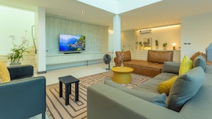 A modern living room with a flat-screen TV, comfortable seating, and a large window. - NicestInPhuket4Br1.5kmBangTao BeachV141 (Choeng Thale)