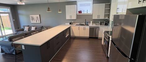 A modern kitchen with a central island, built-in appliances, and a dining area with a sofa.