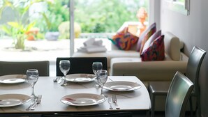 A dining table set with plates, cutlery, and glasses, with a view of greenery outside. - WELCS APARTMENT 282 EMP in villa with swimming pool com (Rosas / Roses)