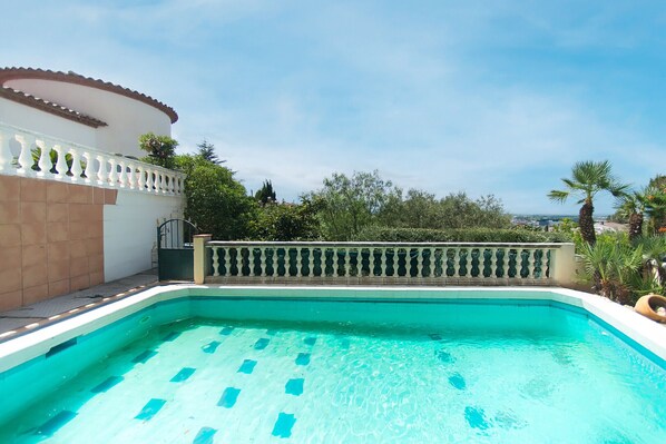 A swimming pool with a white balustrade and a tiled deck area.