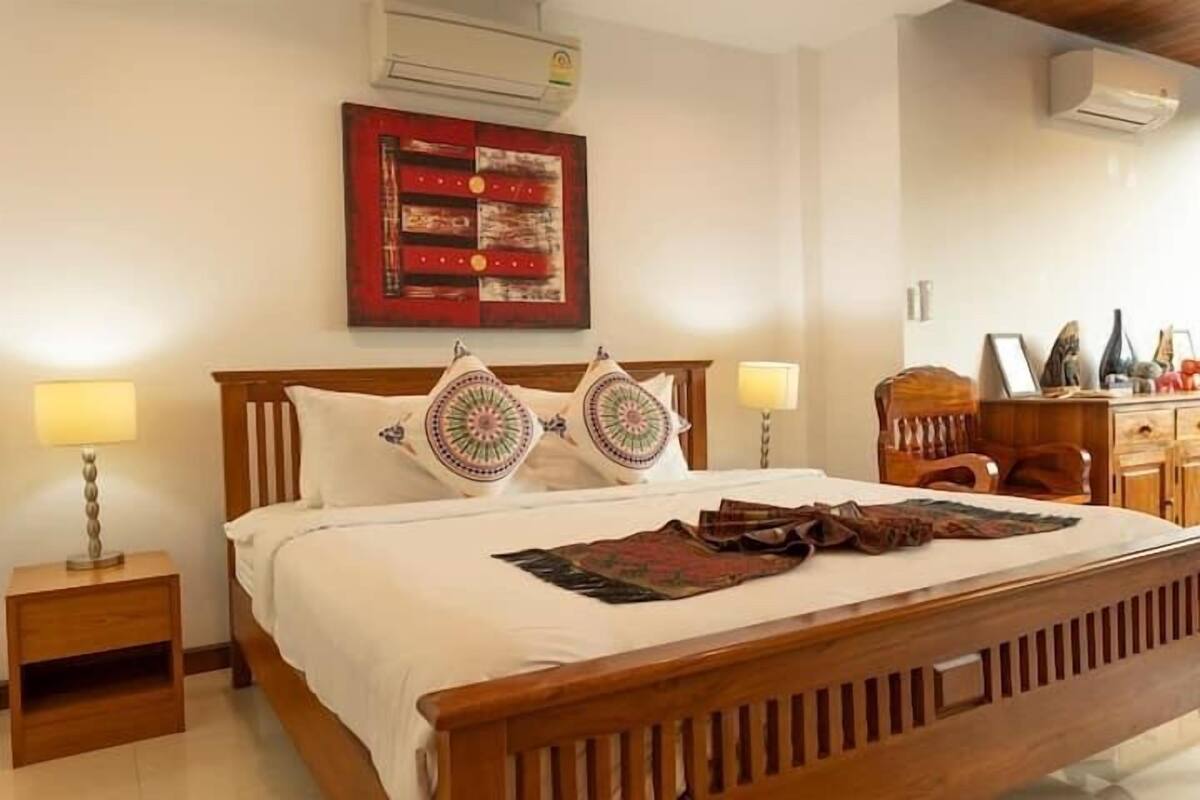 A neatly made bed with a wooden headboard, two bedside lamps, and a decorative pillow.