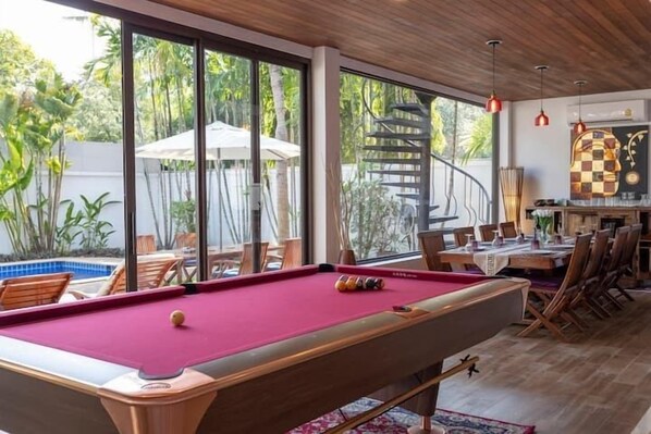 A pool table in a room with large windows, a spiral staircase, and a dining area with chairs and tables. - CoconutPalmsJacuzzipoolhugeproperty v136 (Rawai)