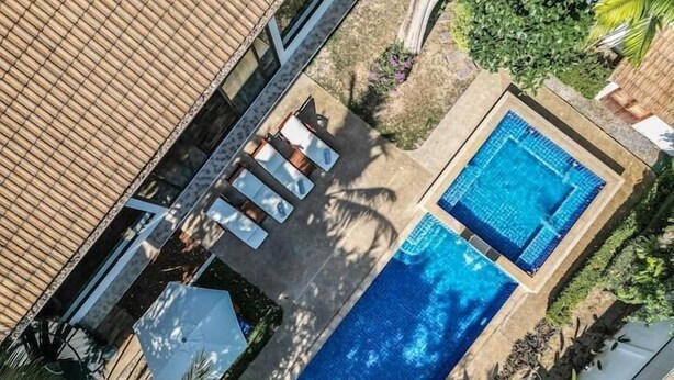 An aerial view of a residential property with a rectangular swimming pool, a covered patio with seating, and surrounding greenery. - CoconutPalmsJacuzzipoolhugeproperty v136 (Rawai)