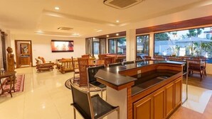 A spacious hotel lobby with a central bar area, comfortable seating, and large windows offering views of the outdoors. - CoconutPalmsJacuzzipoolhugeproperty v136 (Rawai)