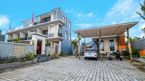 A modern two-story house with a car parked in the driveway and a motorcycle beside it. - Gula Busa Guest House (Sukawati)