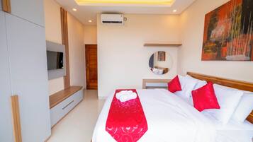 A modern hotel room with a bed, a TV, an air conditioning unit, and a painting on the wall.