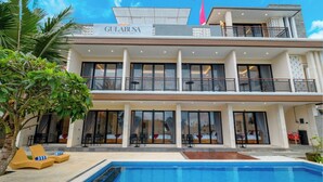 A two-story hotel with a swimming pool, outdoor seating, and large windows. - Gula Busa Guest House (Sukawati)