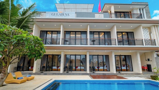 A two-story hotel with a swimming pool, outdoor seating, and large windows. - Gula Busa Guest House (Sukawati)