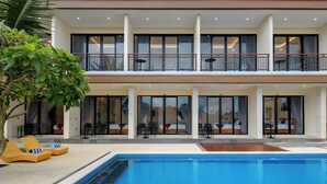 A two-story building with a swimming pool, outdoor seating, and large windows. - Gula Busa Guest House (Sukawati)