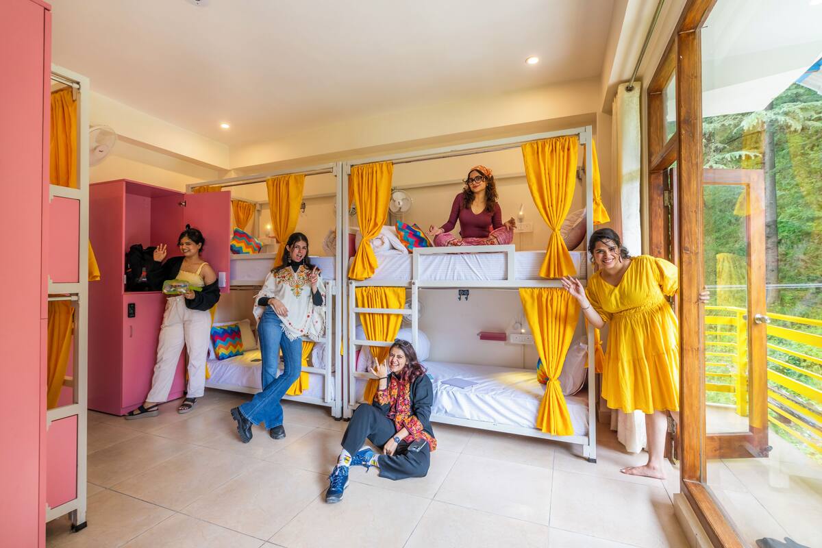 A room with bunk beds, a pink cabinet, and a balcony with yellow railings.