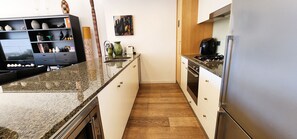 Eine Küche mit einer Granit Arbeitsplatte, Holzschränken, einem Herd und einem Kühlschrank.