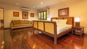 A bedroom with a wooden bed, a sofa, and a nightstand with a lamp. - MassiveHugePool9MinutesWalk to BeachV131 (Choeng Thale)
