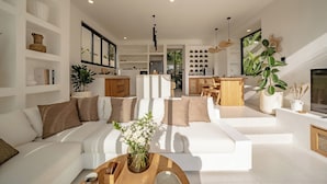 Uma sala de estar moderna com um sofá modular branco, uma mesa de centro de madeira e uma janela grande.