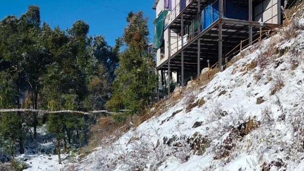 A modern building with a flat roof and multiple windows, situated on a snow-covered slope with a metal staircase leading up. - Snow Adventure Resort (Dhanaulti)