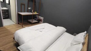 A bedroom with a bed, a wooden floor, a desk, and a mirror. - Snow Adventure Resort (Dhanaulti)