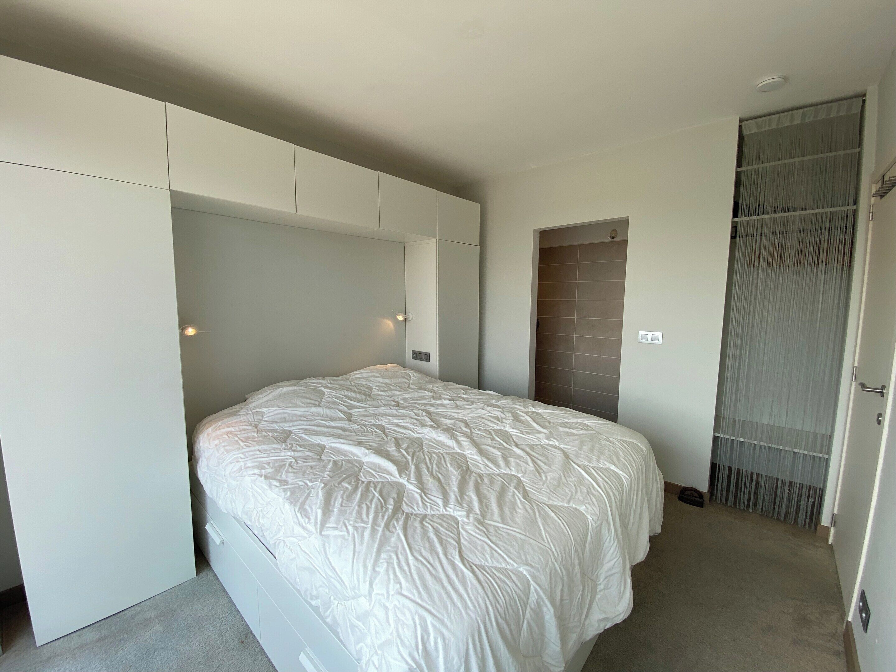 A bedroom with a bed, built-in wardrobe, and a sliding door closet.