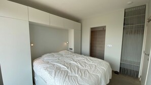 A bedroom with a bed, built-in wardrobe, and a sliding door closet. - Apartment in Nieuwpoort-bad With Sea View (Nieuwpoort)