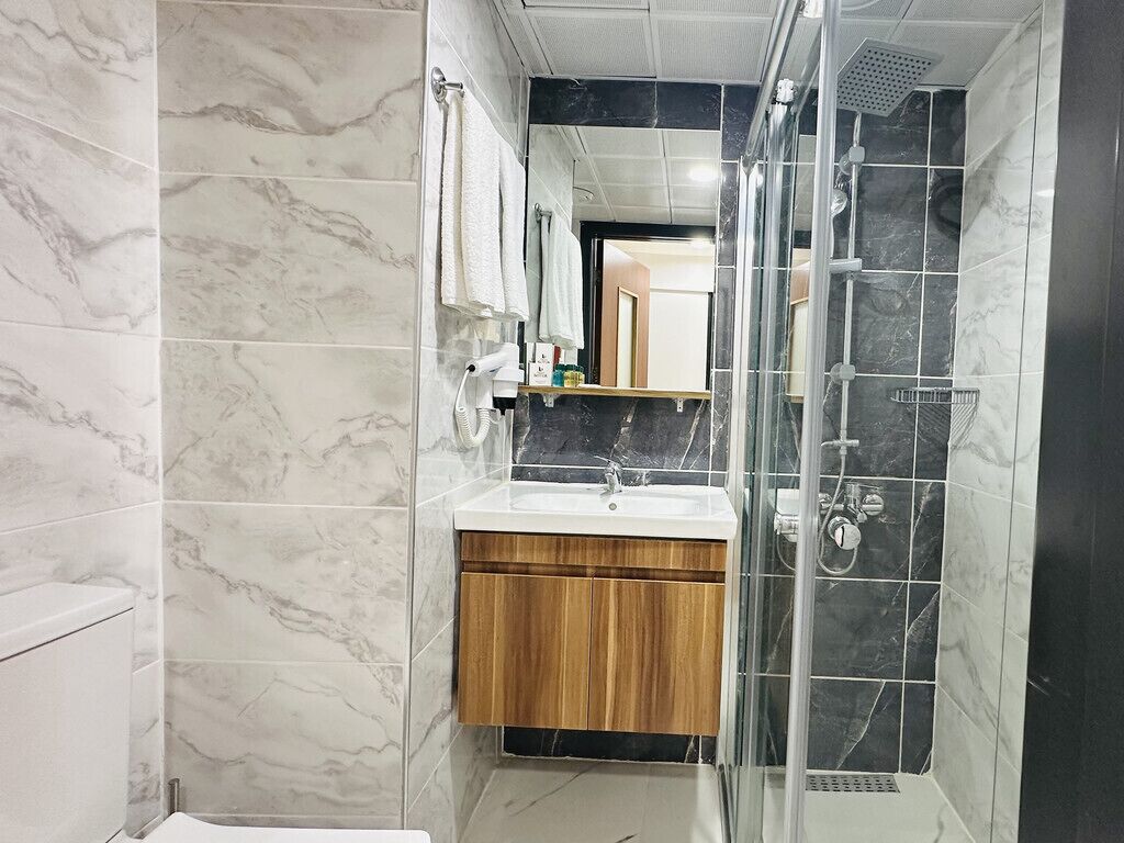 Un baño con tocador de mármol, cabina de ducha y retrete.