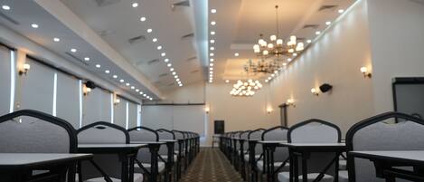 A conference room with rows of tables and chairs, a patterned floor, and a chandelier.